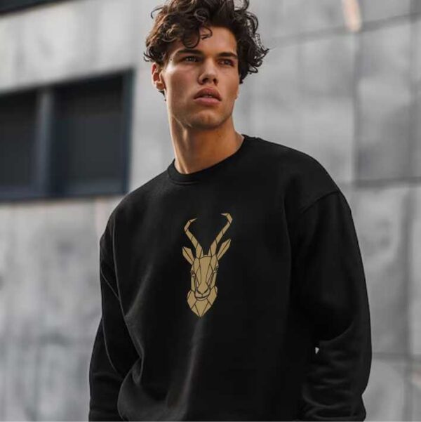 Young man wearing a black sweatshirt with a beautiful gold springbok geometric print. Springbok Sweatshirt South African Clothing